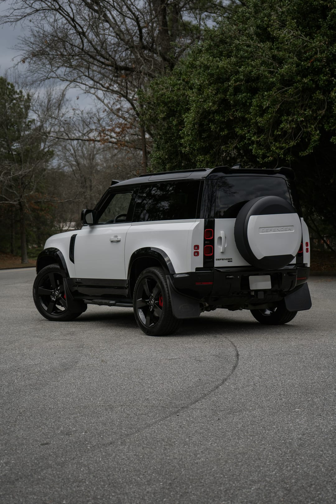 Original photograph of a white Land Rover Defender parked beside trees